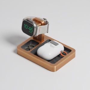 May include: A wooden charging station with a silver smartwatch displaying 10:46. The station includes a white wireless earbud case, two small ring holders, and a small orange loop. The station is designed to hold multiple devices.