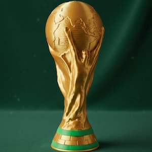 Op de afbeelding: Een gouden trofee met een wereldbol die door handen wordt vastgehouden, met groene en gouden banden op de basis. De achtergrond is donkergroen. Een symbool van overwinning.