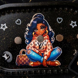 May include: Black rolling tray with a cartoon illustration of a woman in a hoodie and jeans. The tray has gold accents, stars, and hearts. A jewellery box with gold jewellery and lipstick is on the side.