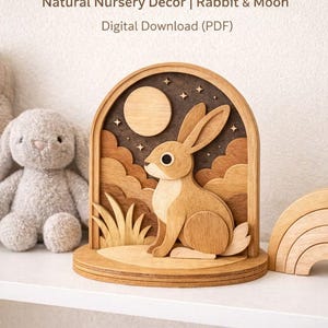May include: Wooden bunny intarsia pattern. A wooden bunny sits in front of a moon and stars. The text reads "Natural Nursery Decor | Rabbit & Moon | Digital Download (PDF)" and "NOT A LAYERED DESIGN | Natural Wood Only".