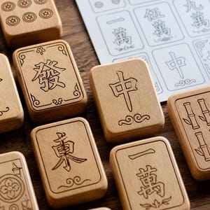 May include: Close-up of wooden Mahjong tiles with engraved Chinese characters and symbols. The tiles are light brown and feature various designs, including bamboo stalks, circles, and characters. A paper with printed Mahjong tile designs is in the background.