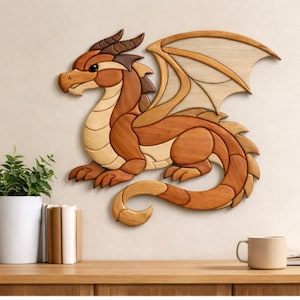 Może przedstawiać: Drewniana dekoracja ścienna przedstawiająca smoka w odcieniach brązu i beżu. Smok wykonany jest z różnych kawałków drewna, ze szczegółowymi skrzydłami i zakręconym ogonem. Dzieło sztuki jest zamontowane na ścianie, z rośliną i kubkiem w tle.