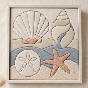 May include: A square framed fabric wall art piece featuring a padded, quilted design of a large fan shell, a spiral conch shell, a sand dollar, and a starfish. The composition uses a palette of beige, soft blue, and muted coral fabric textures.