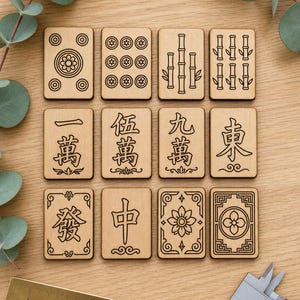 May include: A set of twelve wooden Mahjong tiles with black etched designs. The tiles feature various symbols, including flowers, bamboo stalks, and Chinese characters. A brass ruler and a silver caliper are in the foreground.