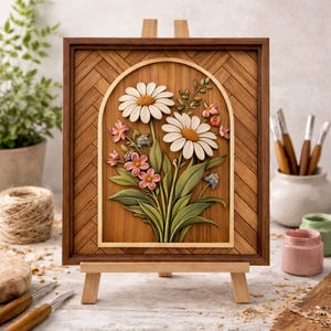 May include: Wooden framed artwork featuring a carved floral design. The artwork showcases two large daisies with white petals and orange centers, surrounded by pink and blue flowers and green leaves. The frame is a dark brown with a herringbone pattern.