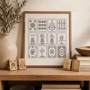 May include: A framed print of Mahjong tiles with black line art on a cream background. Wooden Mahjong tiles are displayed on a wooden shelf. A vase with greenery and a decorative bowl are also visible.