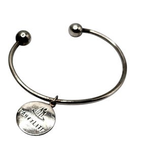Peut inclure: Bracelet jonc ouvert argenté avec un charm rond. Le charm est gravé du mot "PARTY LITE" et d'un logo de trois bougies. Le bracelet a une boule à chaque extrémité.