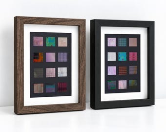 Puede incluir: Dos marcos de pared rectangulares, uno con acabado de veta de madera oscura y otro con acabado negro sólido. Cada marco contiene un paspartú blanco que rodea un inserto negro con una cuadrícula de doce pequeñas impresiones cuadradas abstractas y coloridas.