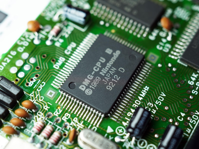 Extreme close-up of the original Nintendo DMG CPU chip and green Game Boy motherboard, highlighting classic 1989 handheld technology – tecnología retro, Retro-Technik, vintage elektronica.