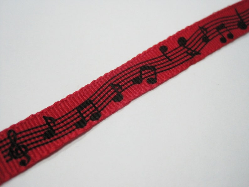 May include: Red ribbon with black musical notes printed on it.