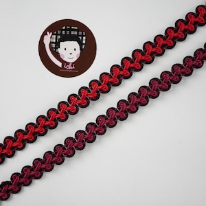 May include: Two strands of black and red trim with a scalloped edge. The trim is made of a woven fabric and has a gradient of red to black.