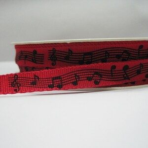 May include: Red ribbon with black musical notes and treble clefs printed on it.