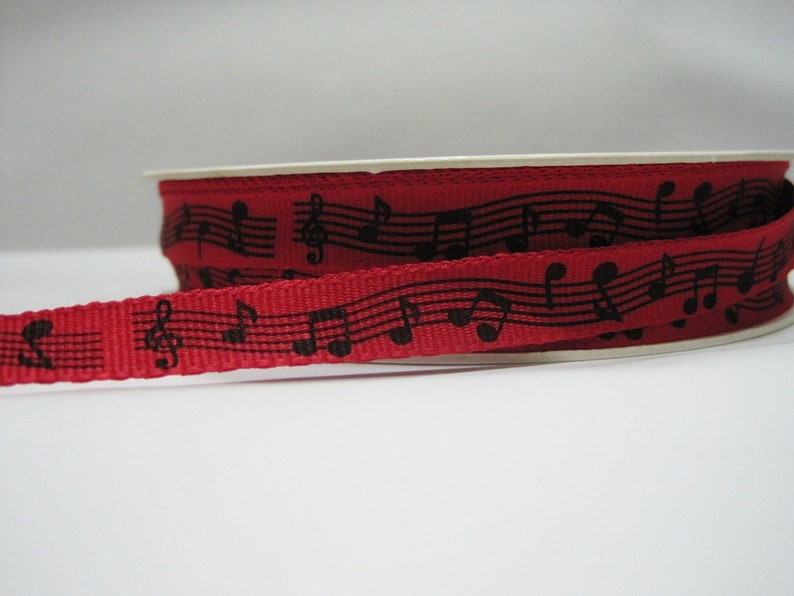May include: Red ribbon with black musical notes and treble clefs printed on it.