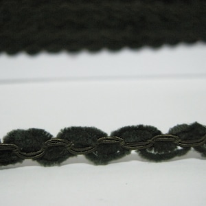 以下が含まれることがあります： 装飾的な編み込みデザインが施された濃い緑色のベルベットトリム。トリムは波状の縁を持っています。