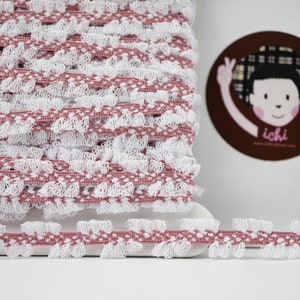 Op de afbeelding: Roze en witte elastische trim met een gekrulde rand. De trim is gemaakt van een zacht, rekbaar materiaal en is perfect om een ​​toets van elegantie aan elk project toe te voegen.
