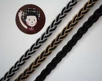 May include: Three braided trim cords in black, gold, and silver. The cords are woven with a simple braid pattern.