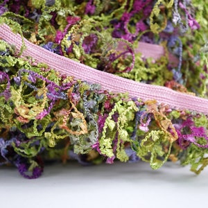 May include: A close-up of a pink and green fringe trim with a variety of colors, including purple, blue, and yellow. The fringe is made of a soft, fluffy material and is perfect for adding a touch of whimsy to any project.