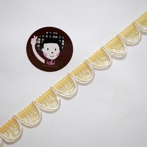 May include: Cream and yellow scalloped decorative trim against a white background. A circular sticker with a cartoon character and the word "ichi" is also visible.
