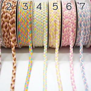 May include: Eight spools of braided trim in various colors, including pink, blue, yellow, and brown. The spools are labeled with numbers 1 through 8.