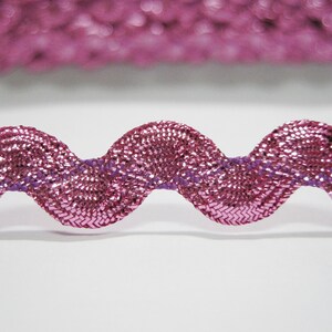 Peut inclure: Garniture m&eacute;tallique rose avec un bord ondul&eacute;. La garniture a un fil violet qui traverse le centre.