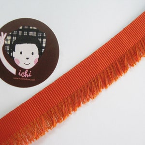 May include: Orange trim with a fringe edge. The trim is ribbed and has a subtle sheen.