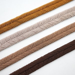 May include: Four different colors of braided trim with a herringbone pattern. The colors are brown, beige, light brown, and gold.