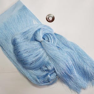 May include: A bundle of light blue fringe, possibly for crafting or decorative purposes. The fringe is neatly bundled and tied, with a woven section at the top. The colour is a soft, pastel blue, suggesting a delicate material.