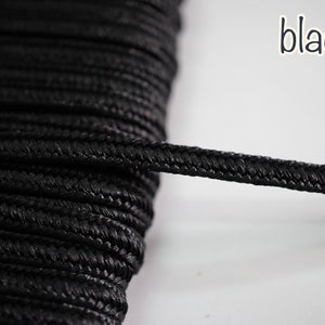 May include: Close-up of black braided cord, showing the texture. The cord is tightly woven and has a smooth, matte finish.