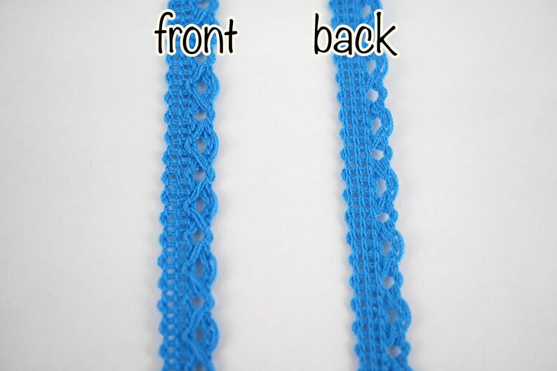 May include: A close-up of a blue lace trim, showing the front and back sides. The lace has a delicate, intricate pattern.