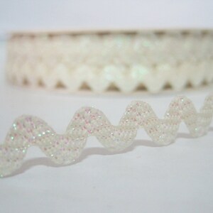 May include: White iridescent trim with a zig-zag pattern. The trim is made of a soft, flexible material and has a subtle shimmer.