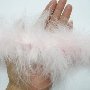 May include: A white feather boa with a pink undertone. The boa is soft and fluffy, and it is perfect for adding a touch of glamour to any outfit.