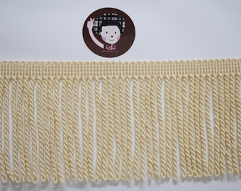 Può includere: Finitura con frange color crema con una parte superiore intrecciata e fili ritorti simili a corde. La finitura è di colore beige chiaro ed è adatta a vari progetti di artigianato e cucito. Sullo sfondo un adesivo circolare con un personaggio dei cartoni animati.