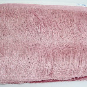 May include: A close-up of a pink fringe trim. The fringe is made of soft, silky fibres and is perfect for adding a touch of elegance to any project.