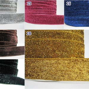 May include: Close-up of five different colors of glitter velvet ribbon. The ribbon is 1 inch wide and is available in silver, pink, blue, brown, and gold.