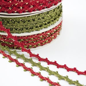 May include: Three spools of gold and red trim with a zig-zag pattern. The trim is made of a soft, woven fabric with a subtle shimmer.