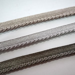 以下が含まれることがあります： 編組のデザインが施された、ベージュ、シルバー、ブラウンの3色のトリム