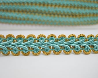 May include: Teal and gold braided trim with a decorative pattern. The trim has a scalloped edge.