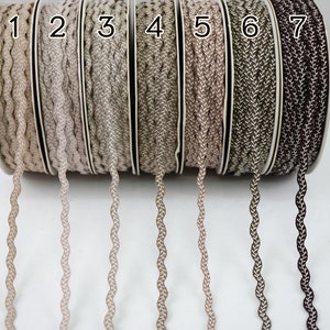 May include: Seven spools of braided trim in various shades of brown, beige, and gray. The spools are labeled with numbers 1 through 7.