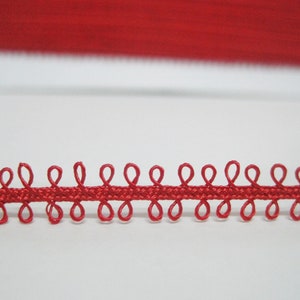 May include: Red trim with a scalloped edge. The trim has a series of small loops along the edge.