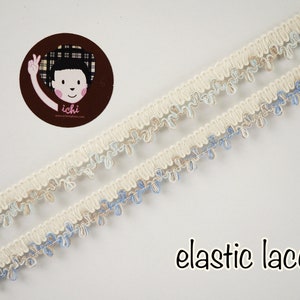 Puede incluir: Borde de encaje elástico blanco con acentos azules y beige. El encaje tiene un borde festoneado y es perfecto para agregar un toque de elegancia a cualquier proyecto.