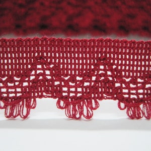 May include: Red crocheted lace trim with a delicate pattern. The trim has a scalloped edge and is perfect for adding a touch of elegance to any project.