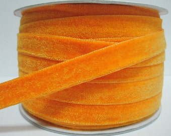 Könnte beinhalten: Eine Spule mit leuchtend orangefarbenem Samtband. Das Band ist weich und hat einen dezenten Glanz.