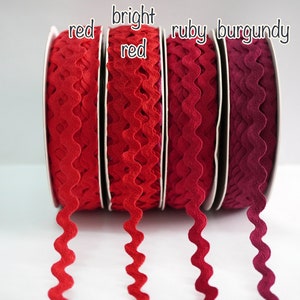 Könnte beinhalten: Vier Spulen mit welligem Besatzband in den Farben Rot, Rot, Rubin und Burgunder.
