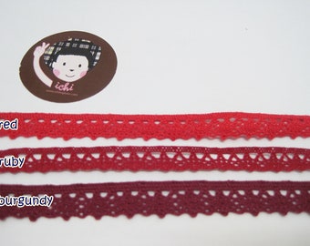 May include: Three samples of lace trim in red, ruby, and burgundy colors. The lace trim has a scalloped edge and a delicate pattern.