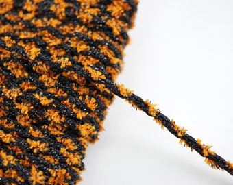 May include: Black and orange twisted cord with a fuzzy texture. The cord is coiled and a section is extended out.