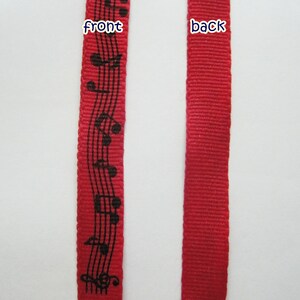 May include: Red ribbon with black musical notes printed on the front. The back of the ribbon is solid red.