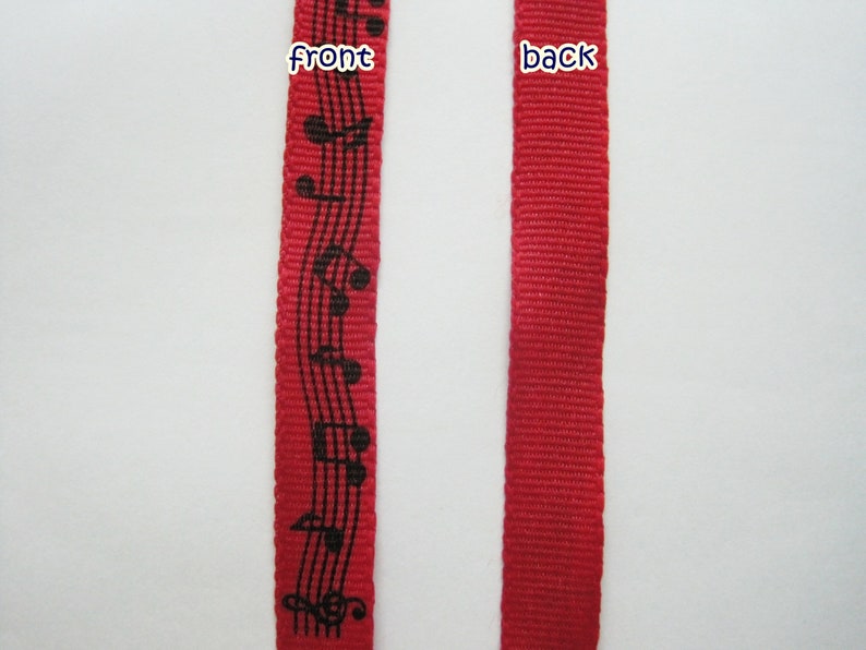 May include: Red ribbon with black musical notes printed on the front. The back of the ribbon is solid red.