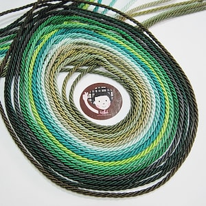 May include: A variety of green, blue, and brown twisted cords arranged in a circular pattern. The cords are all different shades of green, blue, and brown, and they are all twisted together to create a unique look.