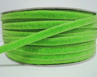May include: A spool of bright green velvet ribbon. The ribbon is approximately 1/4 inch wide and is wound tightly on a spool.