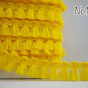 May include: Yellow tassel trim with a scalloped edge. The trim is approximately 2.5 cm wide and has a fringe length of about 2.5 cm. No. 15